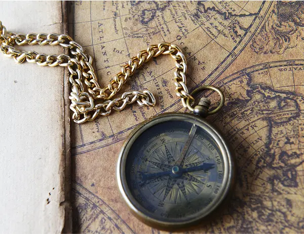 Vintage compass and gold chain lying on an old nautical map, symbolizing navigation and financial guidance